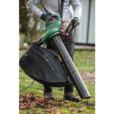 Eine Person benutzt einen Laubbläser, um Blätter im Garten aufzusaugen. Der Laubbläser ist grün und mit einem schwarzen Sammelbehälter ausgestattet.