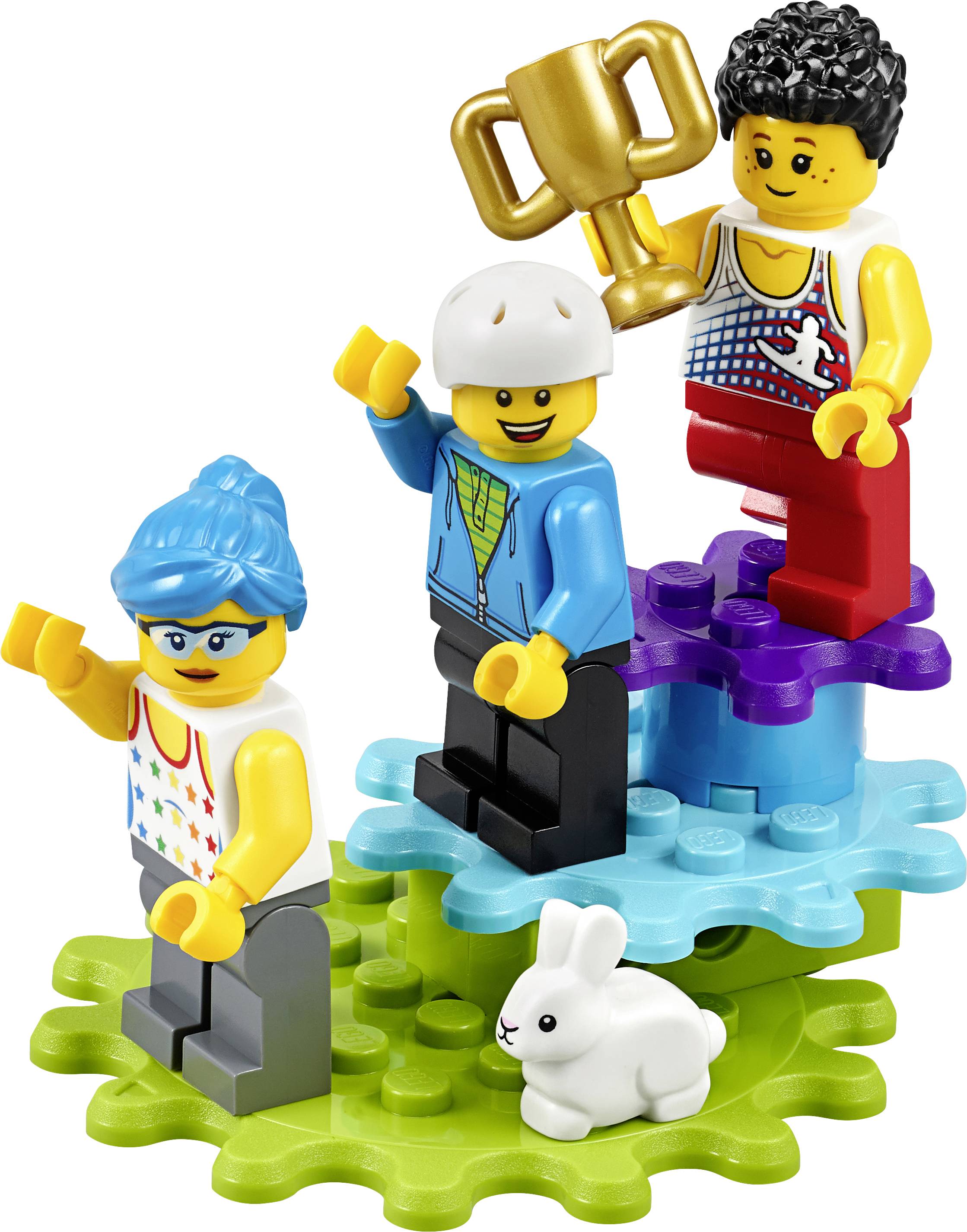 Drei Lego-Figuren stehen auf bunten Sockeln. Eine hält einen goldenen Pokal. Ein Kaninchen sitzt vor ihnen.
