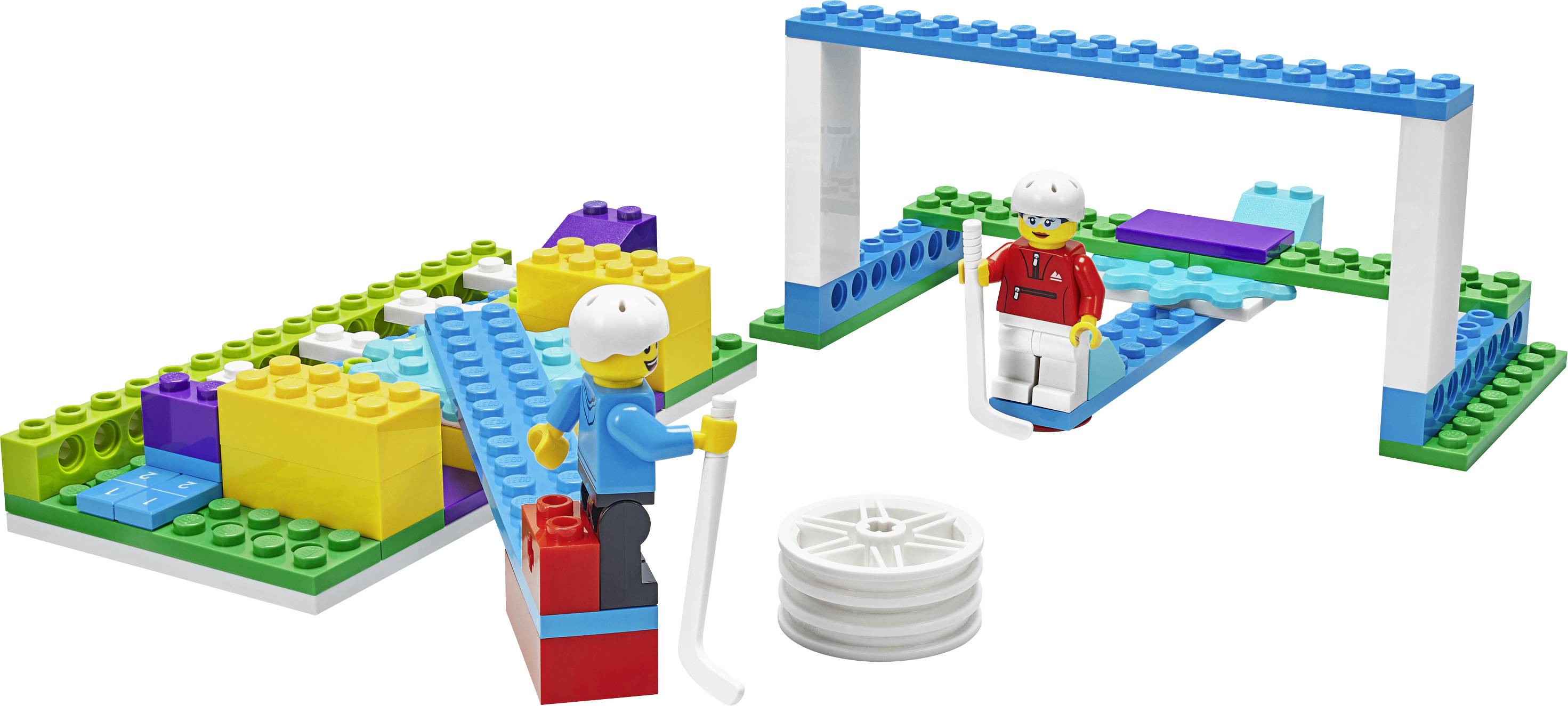Zwei Figuren mit Helmen spielen auf einer bunten Bauplatte mit Legosteinen. Vordergrund: weißes Rad, Hintergrund: Brücke.