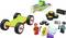 Bausatz mit kleinen Figuren, Rädern und Bauteilen. Enthält ein grünes Autochassis, Reifen und eine Figur mit Helm und Werkzeug.