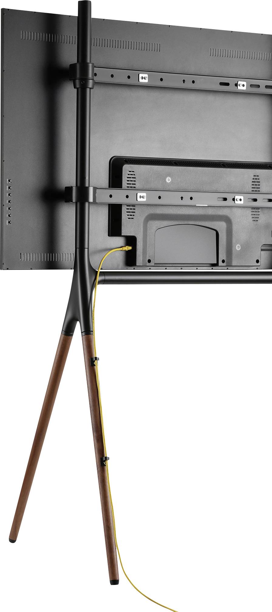 Rückansicht eines Fernsehers auf einem Stativ mit drei Beinen aus Holz; ein gelbes Kabel verläuft entlang eines Stativbeins.