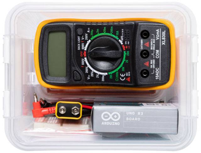 Ein digitales Multimeter in einer transparenten Box zusammen mit einem Arduino-Board und Messkabeln.