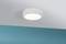 Eine runde, moderne Deckenleuchte strahlt warmes Licht aus und ist an einer weißen Decke montiert. Darunter befindet sich eine türkisfarbene Wand.