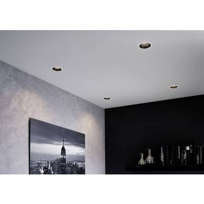 Innenraum mit schwarzer Wand und eingebauten Deckenstrahlern. Ein Foto von einer Skyline hängt an der Wand; daneben Regale mit Büchern.