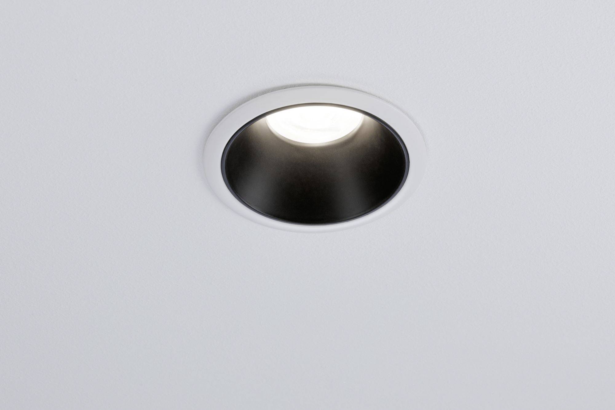 Eine runde, in die Decke eingelassene Deckenlampe, die Licht ausstrahlt. Sie ist von einem silbernen Rahmen umgeben.