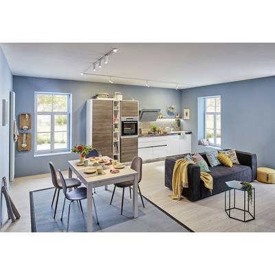 Ein modernes Wohnzimmer mit offener Küche. Links steht ein Esstisch mit Geschirr, rechts ein dunkles Sofa mit Kissen und Decke.