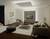 Modernes Wohnzimmer mit beige Sofa, mittigem Couchtisch, Fernseher an der Wand, Teppich und dekorativen Elementen. Elegantes Ambiente.