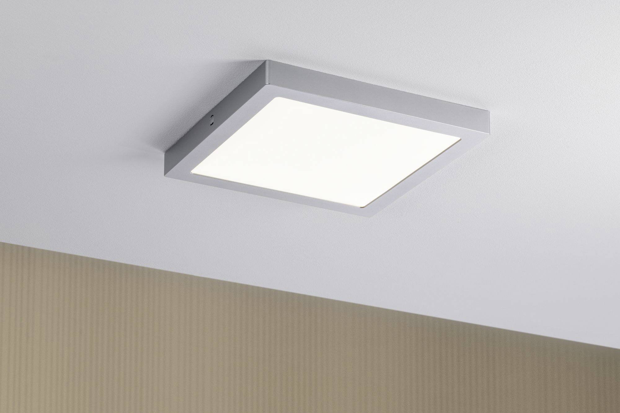 Quadratische, moderne Deckenleuchte mit weißem Licht, montiert an einer Decke mit beigem Hintergrund.