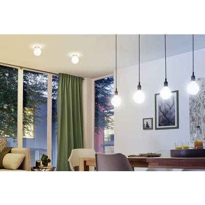 Helles Wohnzimmer mit modernen Hängelampen, Glasschiebetüren und grünen Vorhängen. Im Hintergrund sind Bäume sichtbar.