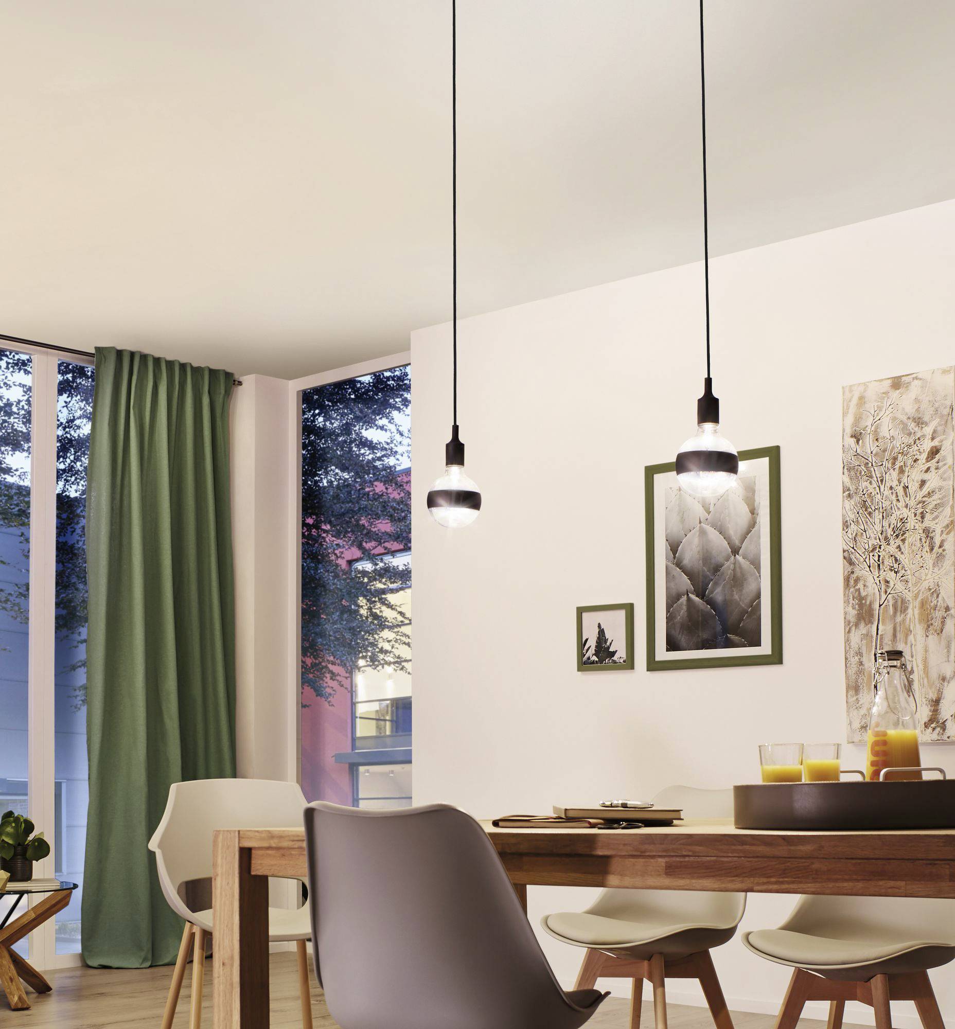 Esszimmer mit Holztisch, Stühlen und zwei hängenden Lampen. Auf dem Tisch stehen Getränke. Durch Fenster ist ein bewaldeter Außenbereich sichtbar.