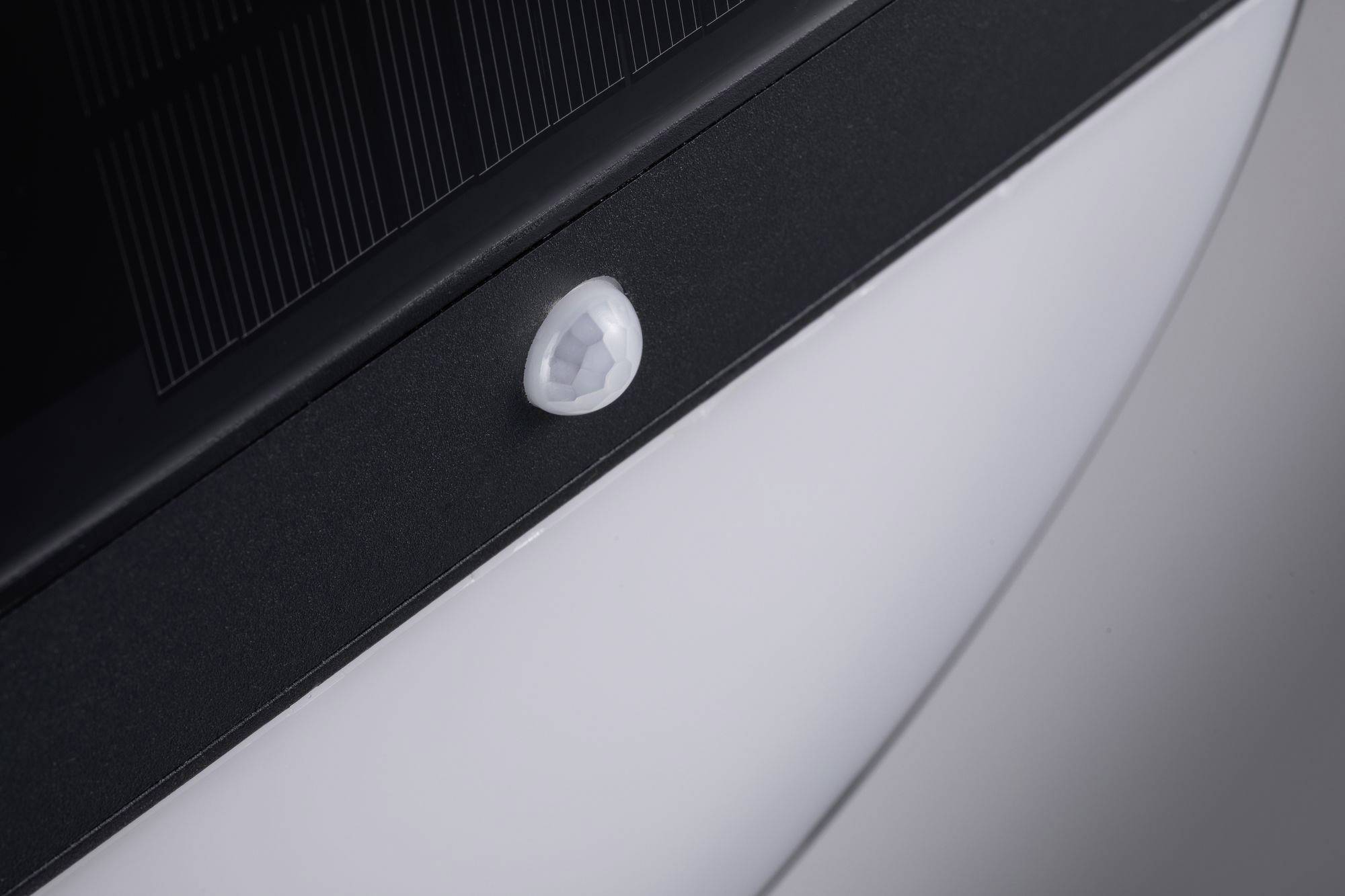 Nahaufnahme eines Bewegungssensors an einem Gehäuse. Der Sensor ist klein und rund, eingebettet in eine schwarze Oberfläche.