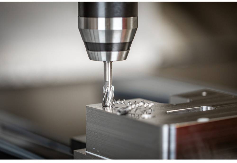 Ein Fräskopf bearbeitet Metall auf einer CNC-Werkbank, wobei Metallspäne entstehen. Die Szene zeigt Präzisionsbearbeitung.