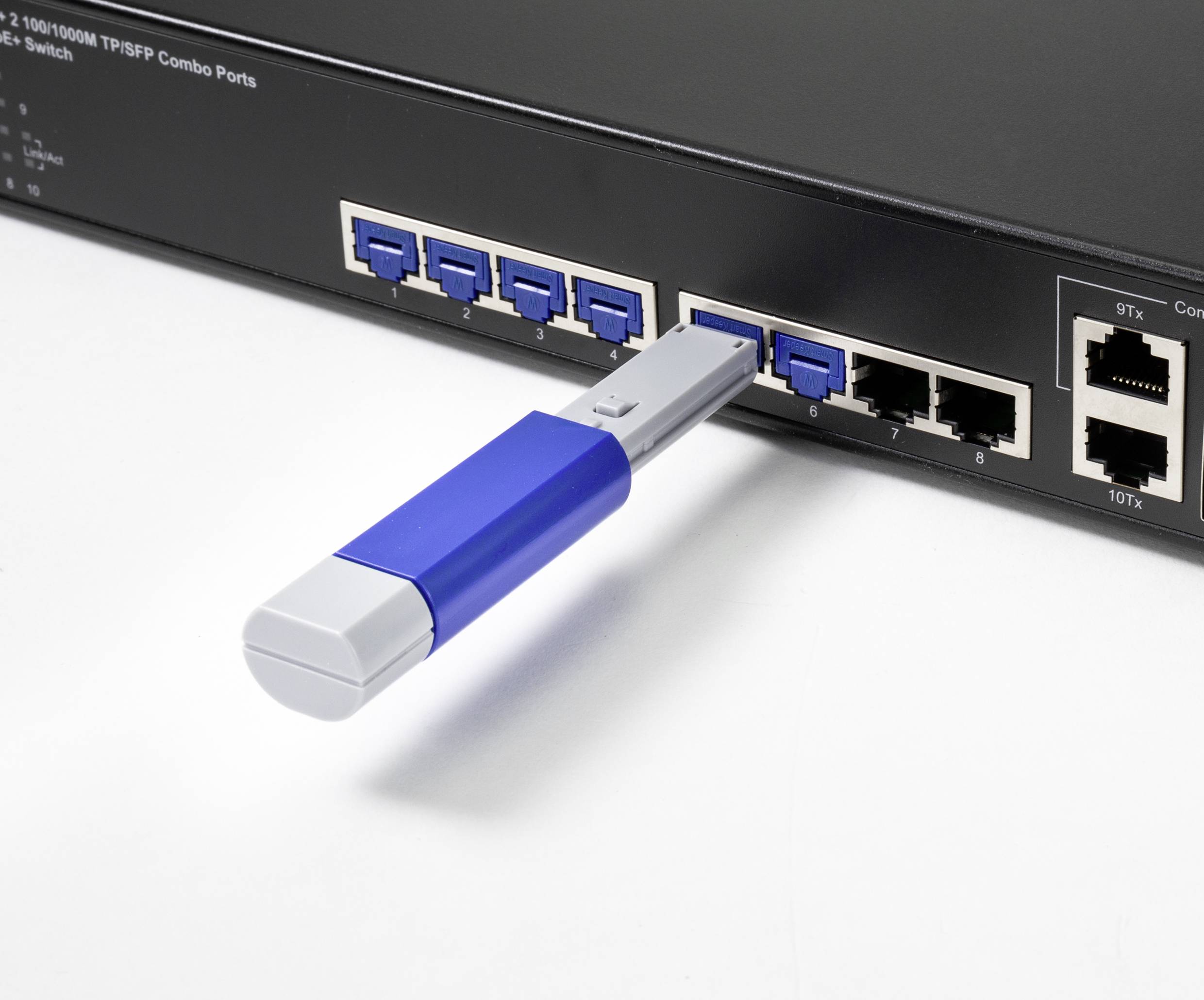 Ein USB-Stick ist in einem Netzwerk-Switch mit mehreren blauen und schwarzen Ethernet-Ports eingesteckt.