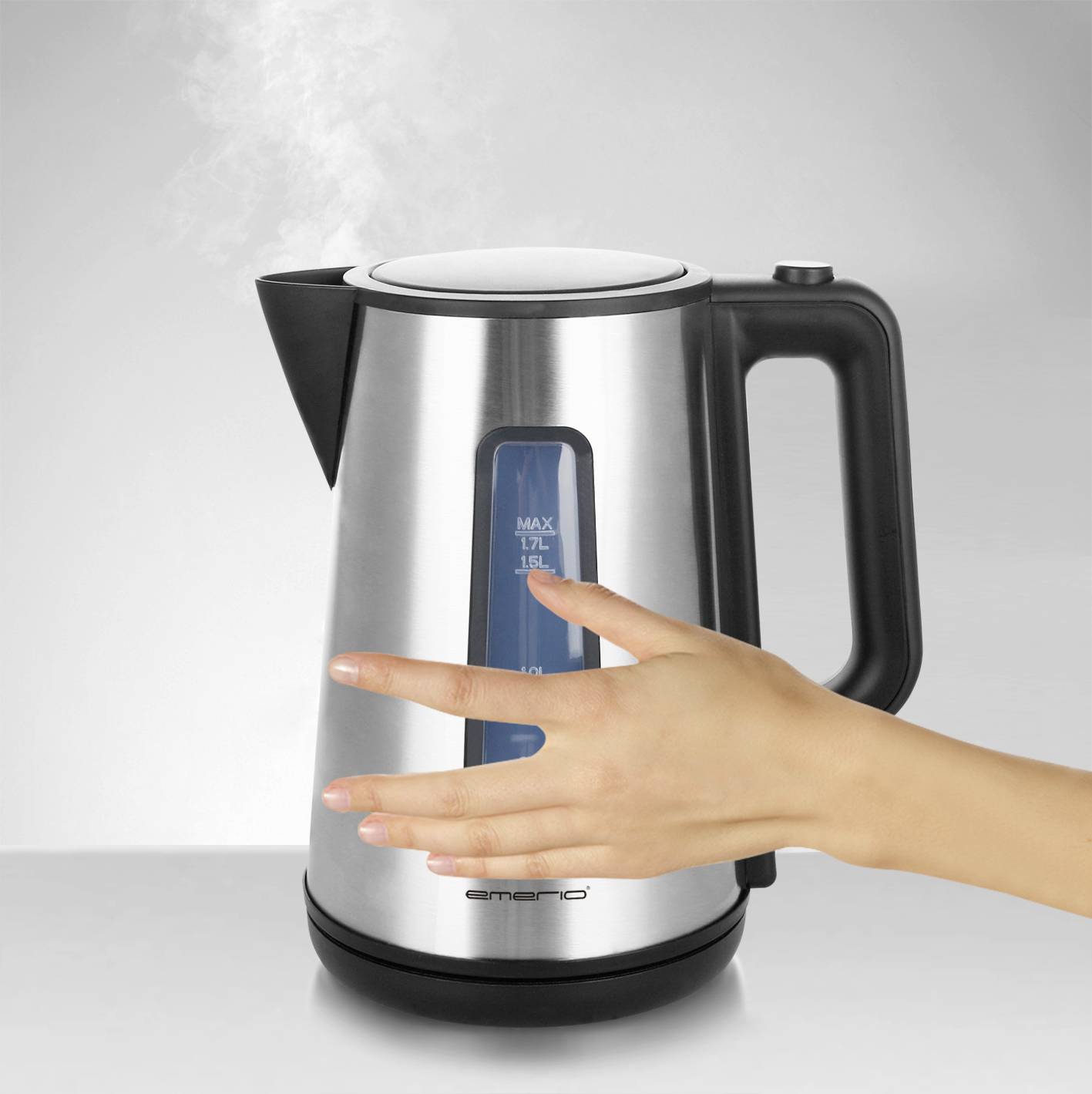 Eine Hand nähert sich einem dampfenden Wasserkocher aus Edelstahl, was auf Vorsicht beim Umgang mit heißem Wasser hinweist.