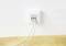 Eine weiße Netzwerkwanddose mit drei angeschlossenen Ethernet-Kabeln vor einer weißen Wand auf einer Holzoberfläche.