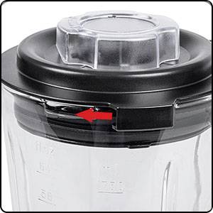 Glasbehälter mit schwarzem Deckel, roter Pfeil zeigt auf eine Öffnung. Könnte für Mixer oder Küchenmaschine verwendet werden.