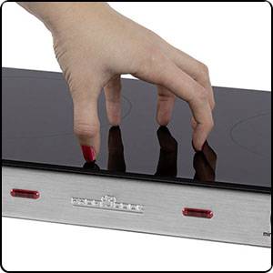 Eine Hand zeigt die Bedienung eines Induktionskochfelds, bei dem ein Schieberegler zur Steuerung der Hitze verwendet wird.