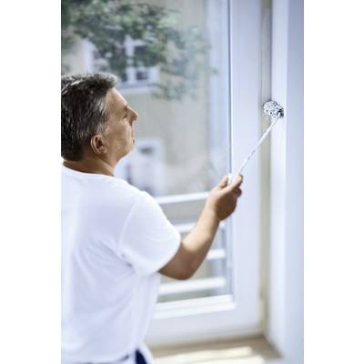 Ein Mann streicht mit einer Farbrolle den Fensterrahmen weiß. Er konzentriert sich auf seine Arbeit, während Tageslicht durch das Fenster fällt.
