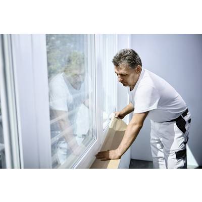 Ein Mann in Arbeitskleidung justiert ein Fensterbrett in einem hellen Raum.