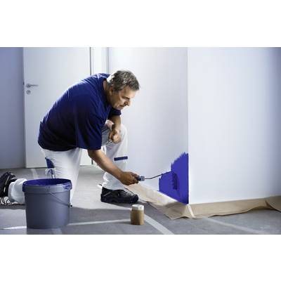 Ein Mann kniet und streicht eine Wand mit blauer Farbe. Der Boden ist mit Abdeckpapier geschützt. Ein Eimer Farbe steht neben ihm.