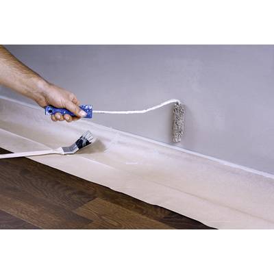 Eine Person streicht mit einer Farbrolle die Wand grau, während ein Pinsel auf dem Boden liegt. Der Boden ist mit Folie abgedeckt.