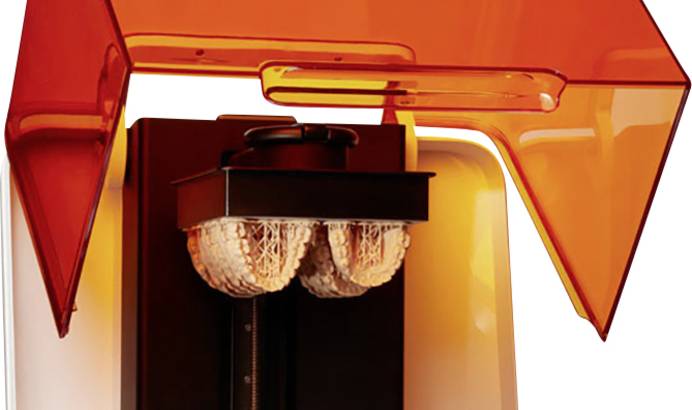 Industrie Stereolithografie-Drucker Formlabs mit unter der Druckplatte hängenden Druckobjekten Auf dem Bild sieht man einen Stereolithografie-Drucker, bei dem die Druckobjekte (Gebissmodelle) unter der Druckplatte hängen.