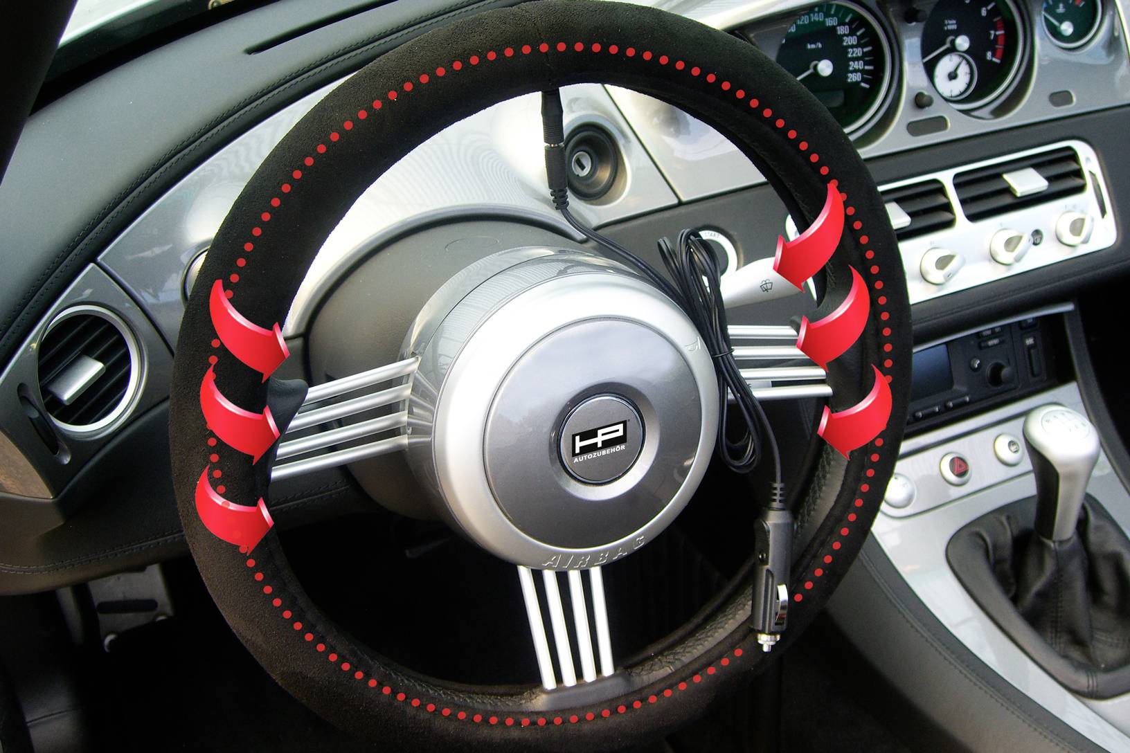 Lenkradschutz mit rotem Heizelement über einem Autolenkrad. Kabel verbindet das Element mit dem Stromanschluss. Anzeigen im Hintergrund.