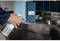 Eine Hand sprüht Reinigungsmittel auf eine Edelstahloberfläche in einer Küche. Im Hintergrund steht eine Schachtel mit weiteren Reinigungsutensilien.