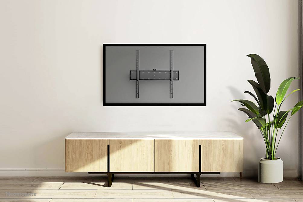 Ein leeres Wohnzimmer mit einem Wandfernsehhalter über einem eleganten, hölzernen Sideboard. Rechts steht eine hohe Zimmerpflanze.