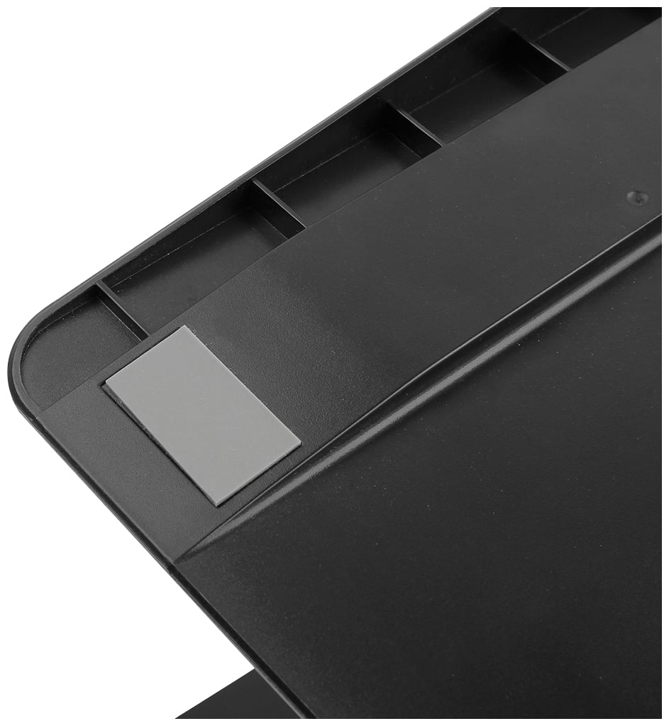 Schwarze Kunststoffoberfläche mit einer grauen Gummiecke; möglicherweise Teil einer Tisch- oder Geräteabdeckung.