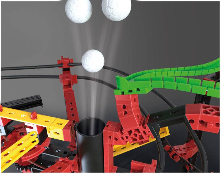 Bunte Kugelbahn aus roten, gelben und grünen Kunststoffteilen, darauf weiße Kugeln. Einige Kugeln sind in Bewegung und rollen nach unten.