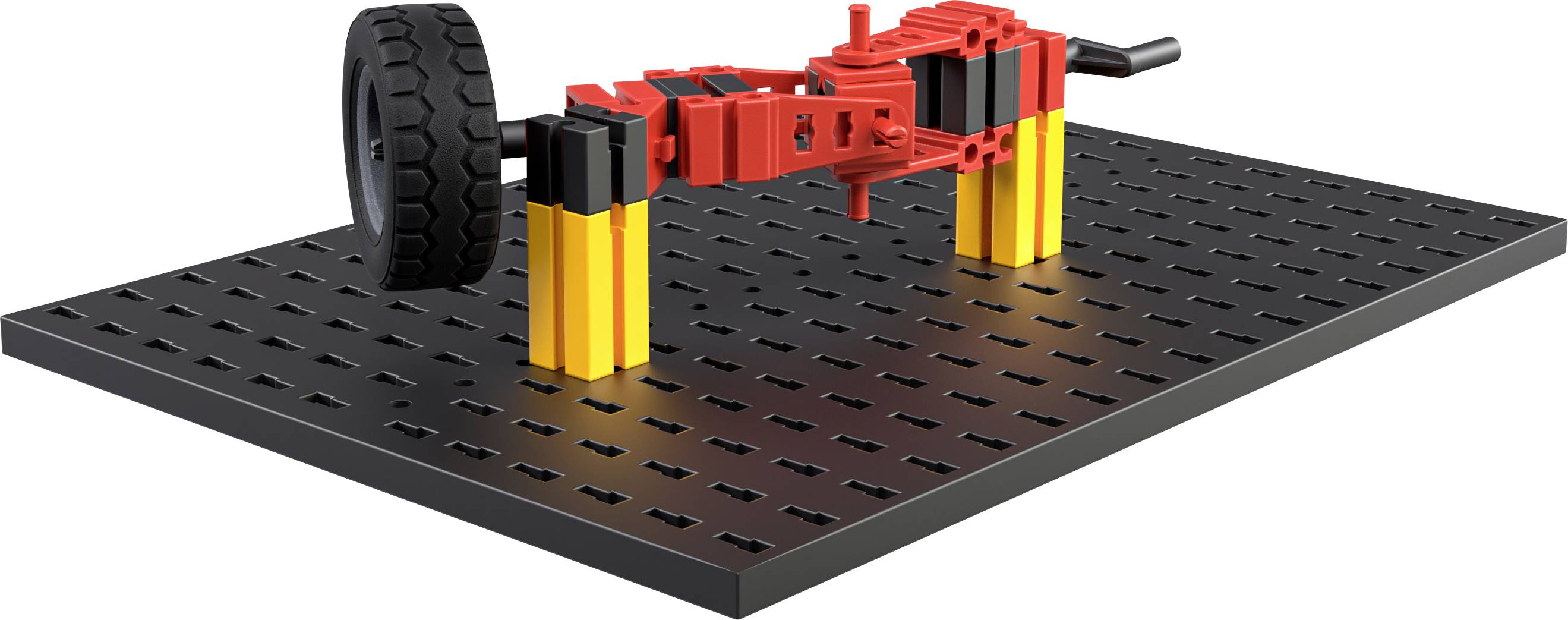 Ein Modellauto-Mechanismus auf einer schwarzen Lochplatte, bestehend aus roten und gelben Bauteilen, zeigt eine Radaufhängung.