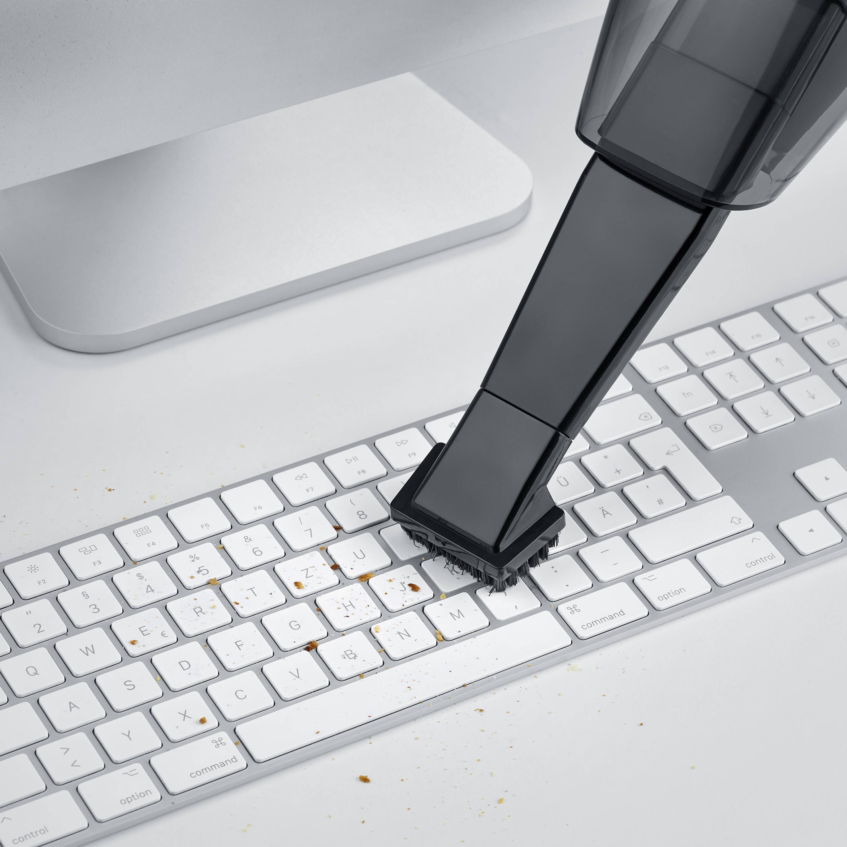 Eine Tastatur wird von Krümeln mit einem kleinen Handstaubsauger gereinigt.