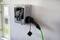 Eine an der Wand montierte Ladestation mit angeschlossenem Ladekabel, bereit zum Aufladen eines Elektroautos.