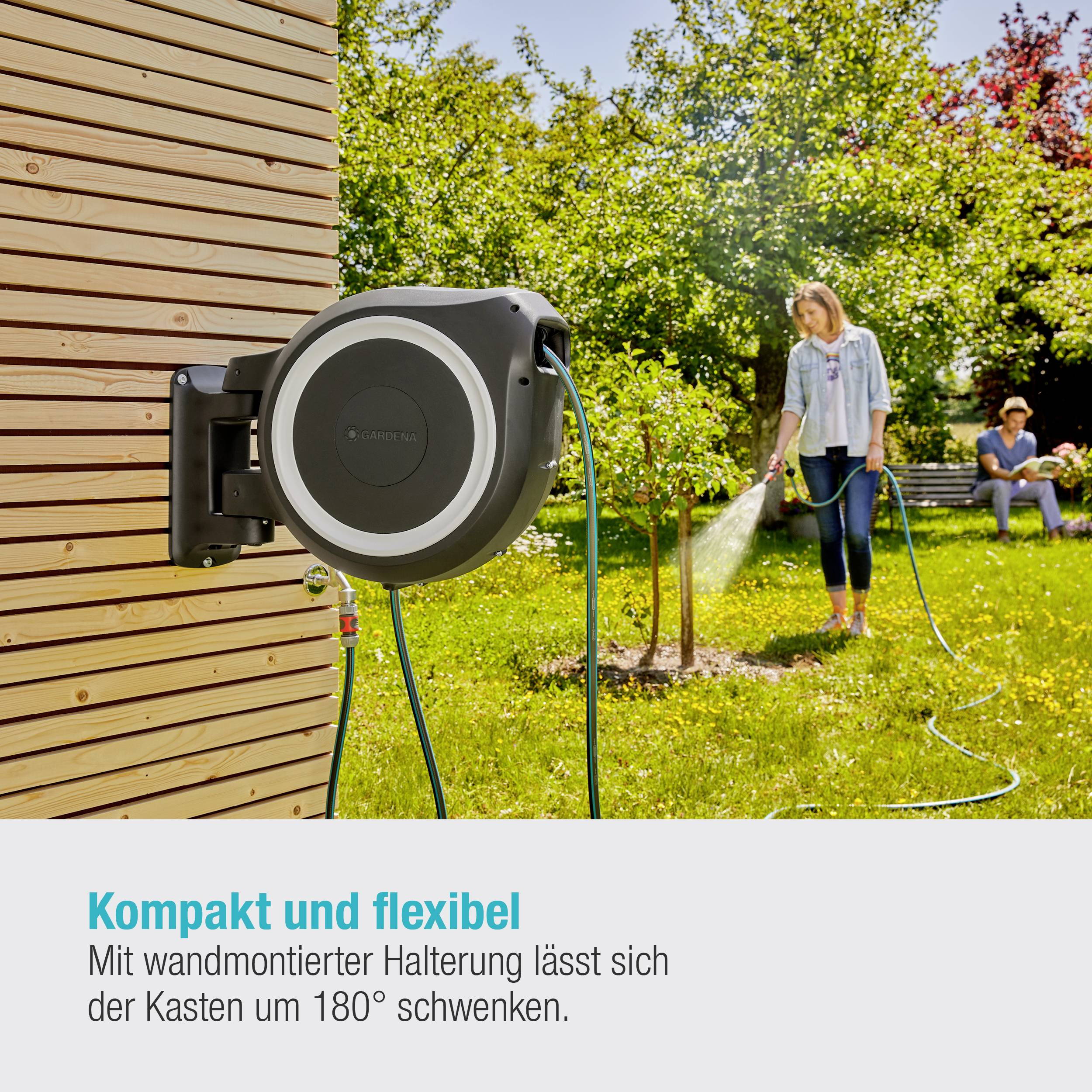 Gartenszene mit einer Person, die Pflanzen bewässert, während ein Schlauch an einem drehbaren, wandmontierten Halter befestigt ist.