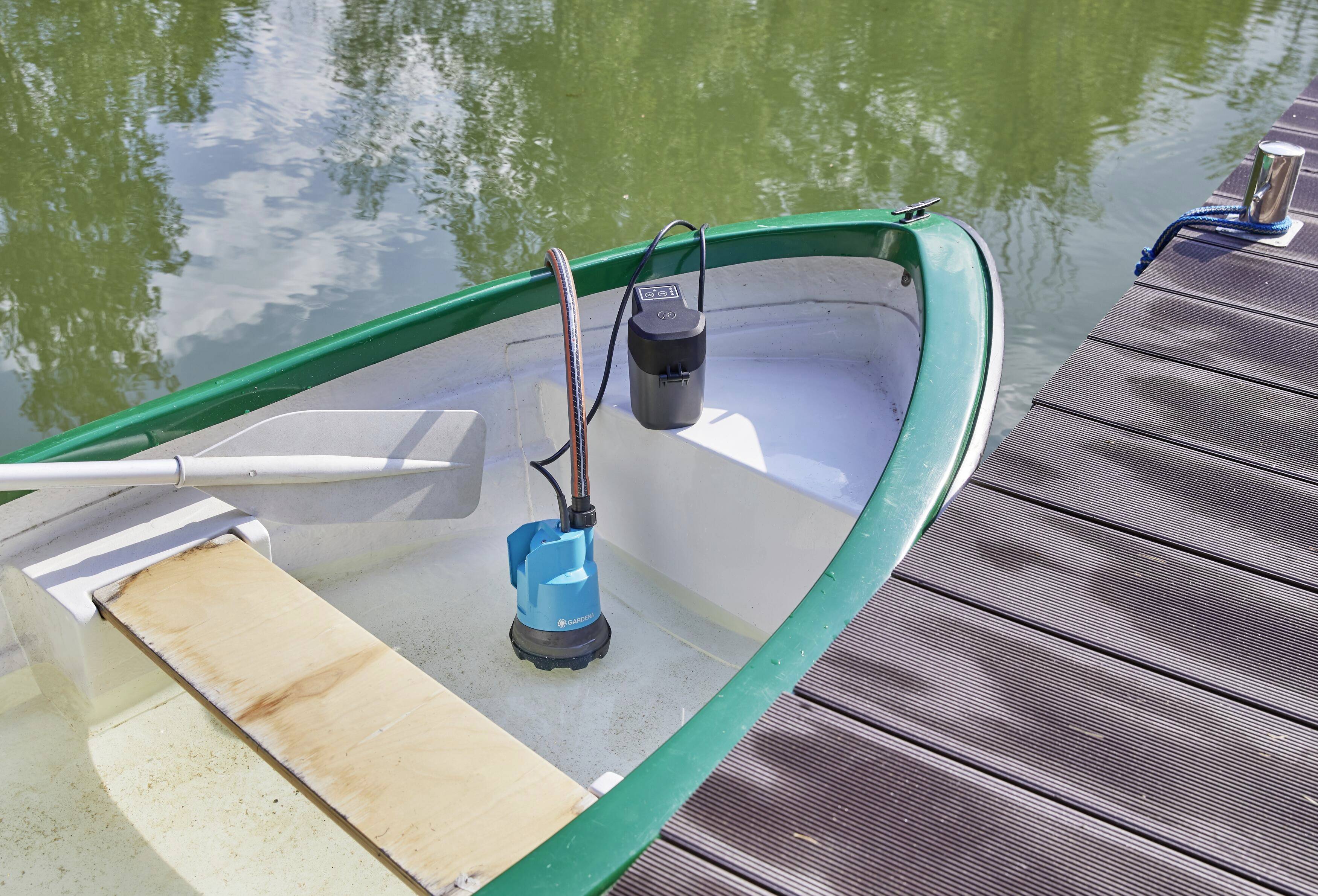 Ein kleines Ruderboot mit einem Wasserauslaufgerät zur Wasserentfernung liegt am Steg eines ruhigen Sees festgemacht.
