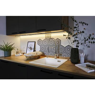 Moderne Küche mit Holzarbeitsplatte, weißem Waschbecken und sechseckigen Kacheln als Rückwand. Pflanzen und Dekor auf der Theke.