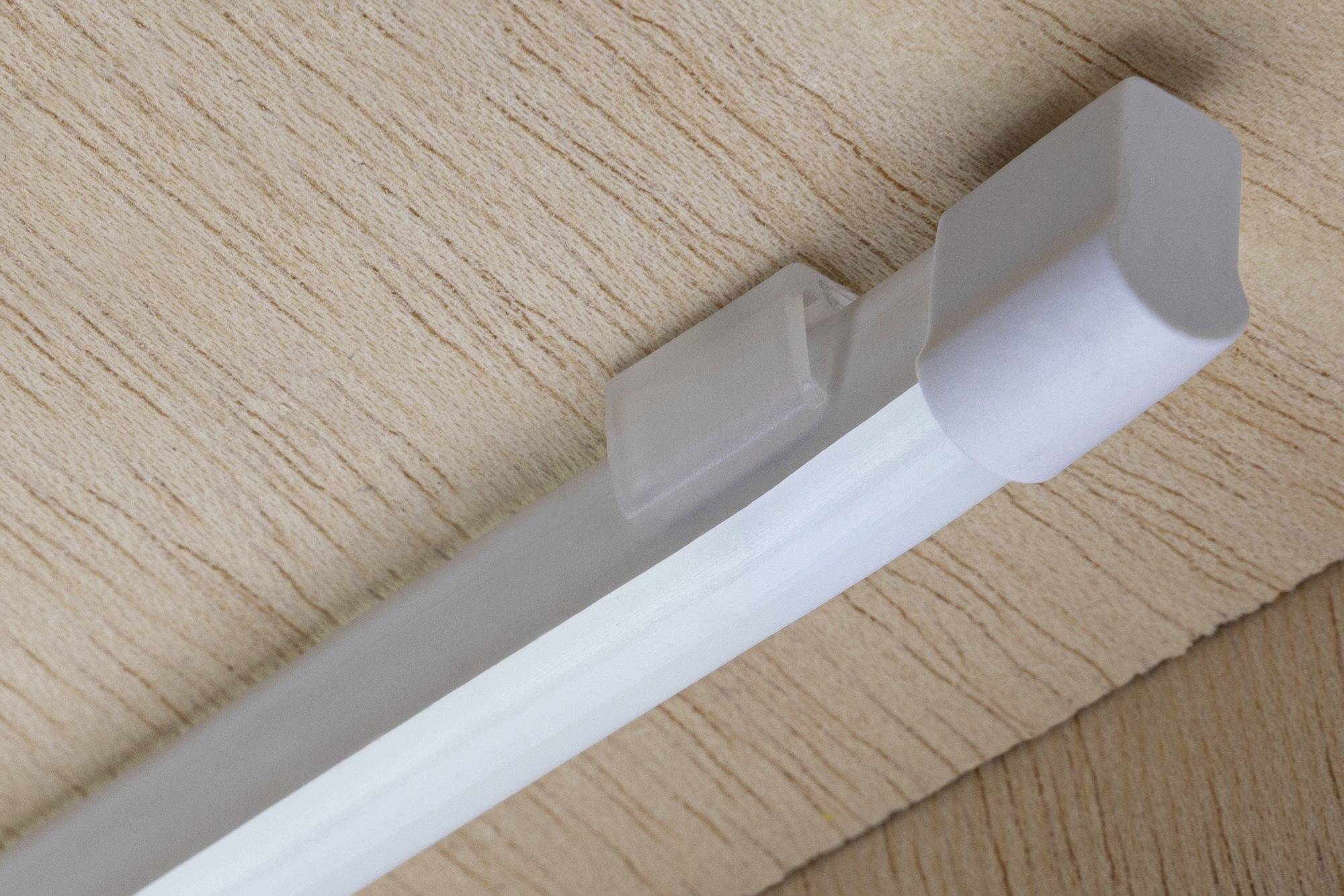 Eine weiße LED-Leiste ist an einer holzartigen Oberfläche befestigt.