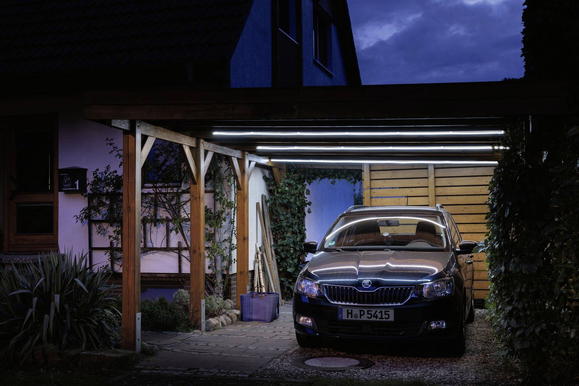 Auto steht nachts beleuchtet unter einem Carport.灯光罩住夜晚停在车棚下的汽车