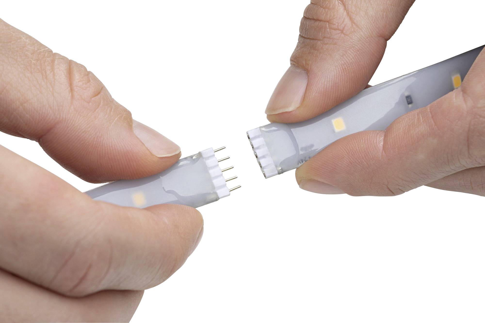 Zwei Hände verbinden zwei Teile eines LED-Lichtstreifens, wobei metallische Pins als Verbinder sichtbar sind.