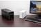 Computerarbeitsplatz mit Monitor, Tastatur, schwarzem und weißem Computergehäuse auf einem Holztisch. Im Hintergrund ist eine Landschaft auf dem Bildschirm zu sehen.