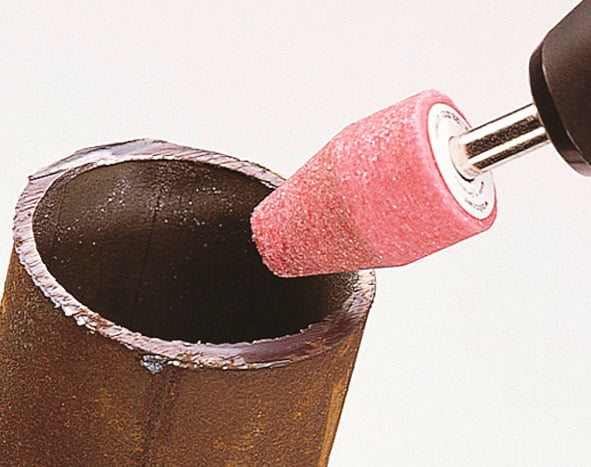 'Nahaufnahme eines Braunrohrs, das innen mit einem rotierenden Schleifaufsatz poliert wird.'