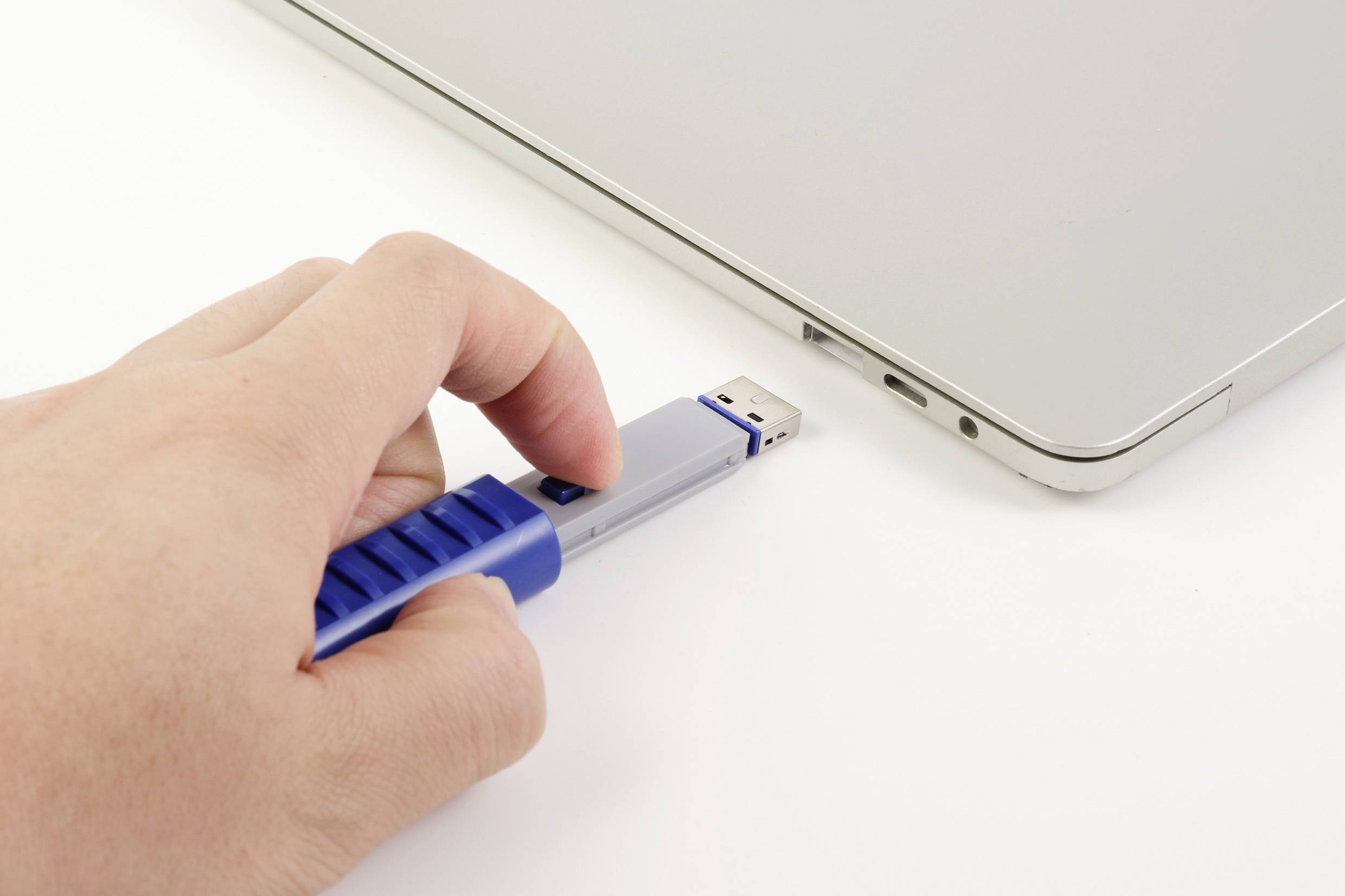 Eine Hand steckt einen USB-Stick in einen Laptop ein.