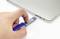 Hand steckt blauen USB-Stick in einen Laptop ein.