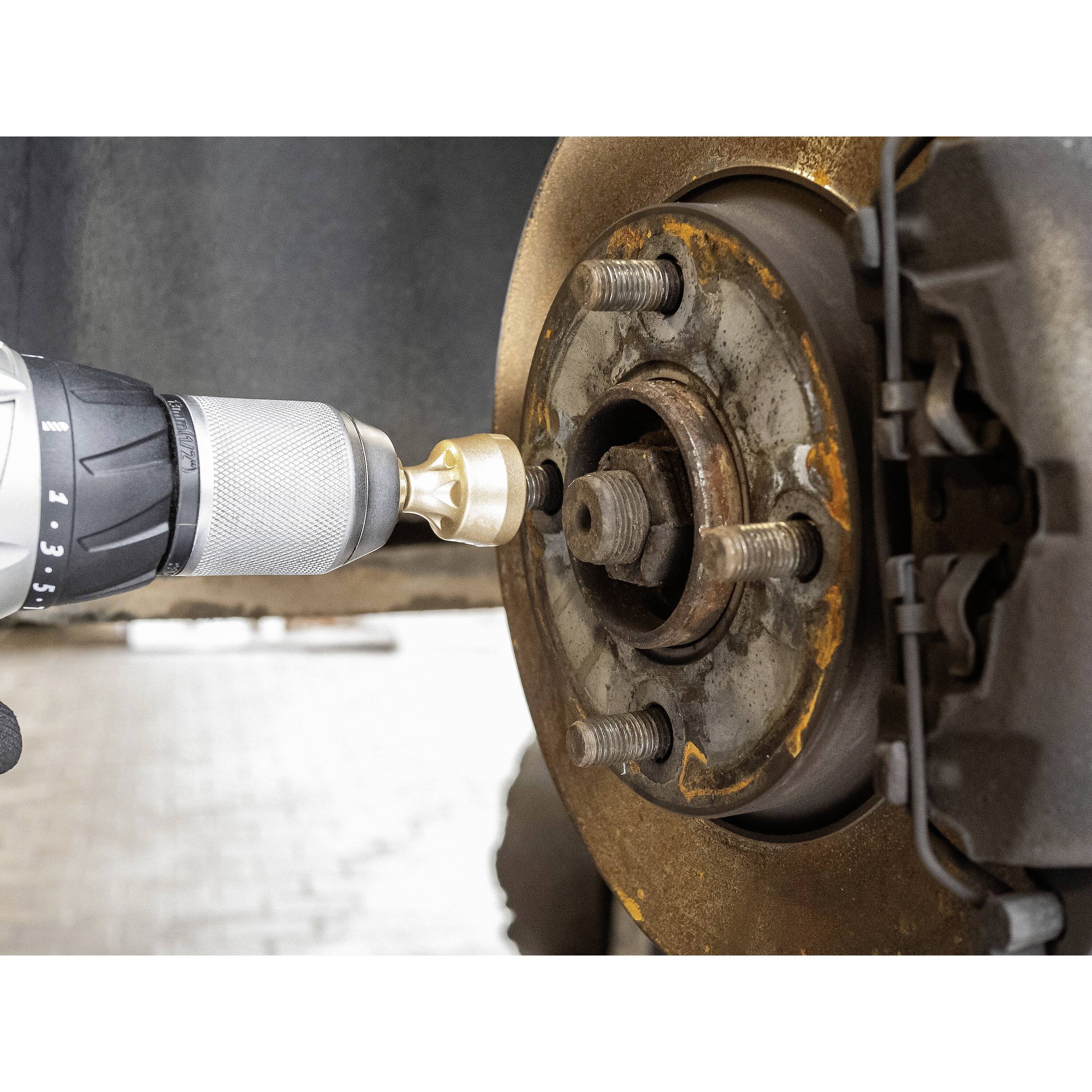 Eine Bohrmaschine entfernt Rost von einer Autoscheibenbremse. Der Aufsatz dreht sich an der verrosteten Bremsscheibe.