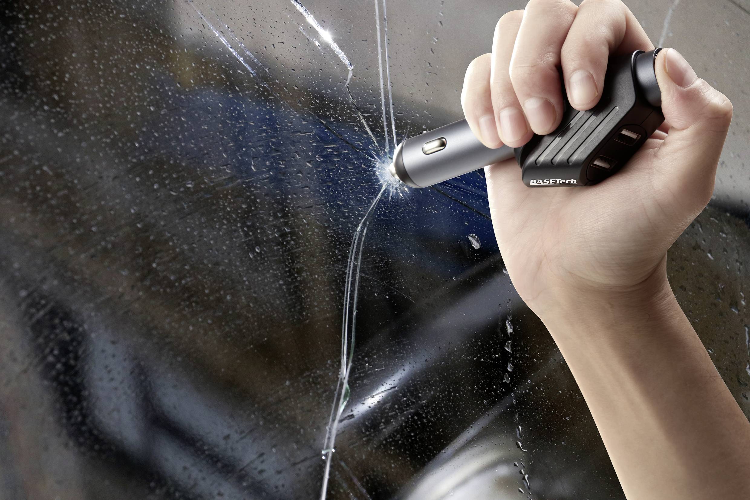 Hand nutzt einen Notfallhammer, um eine Autoscheibe zu zerbrechen.