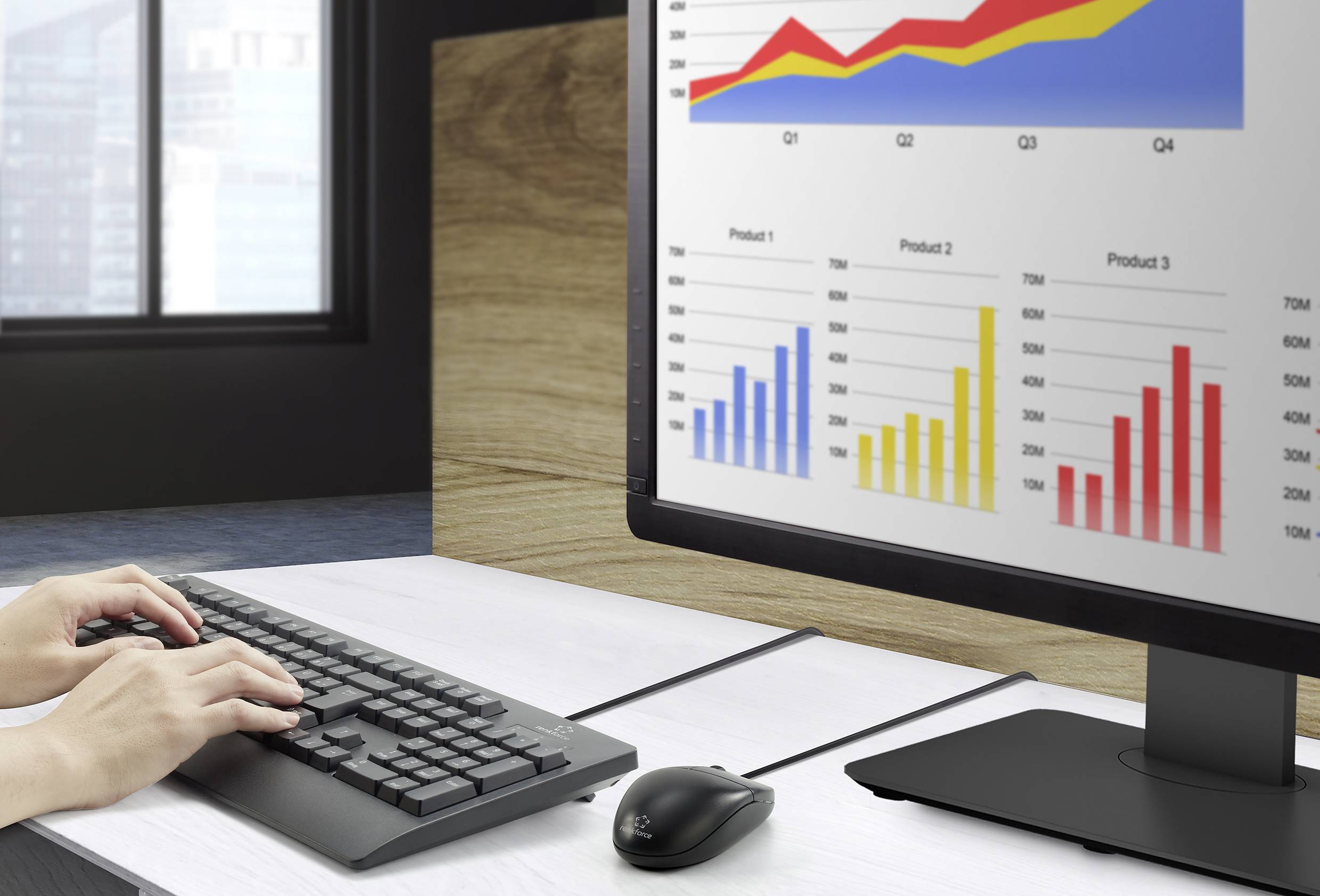 Person tippt am Computer, während auf dem Monitor farbige Balken- und Liniendiagramme zu Verkaufszahlen für Q1 bis Q4 angezeigt werden.