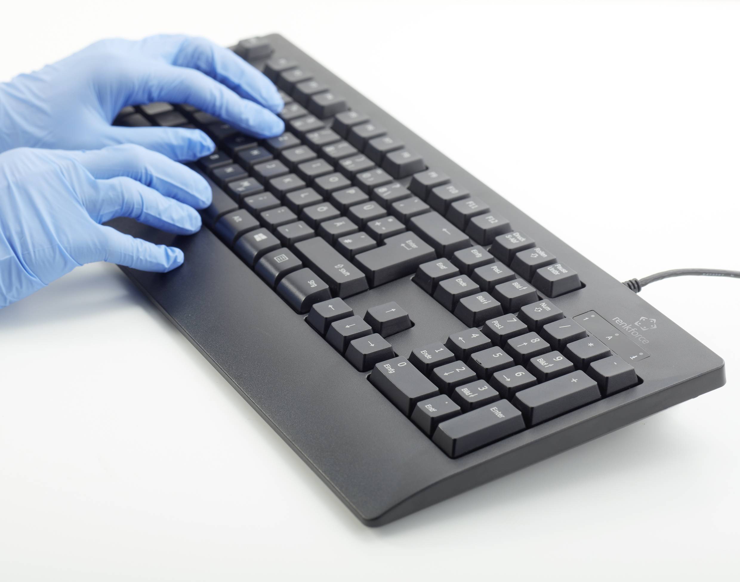 Hände in blauen Latexhandschuhen tippen auf einer schwarzen Computertastatur.