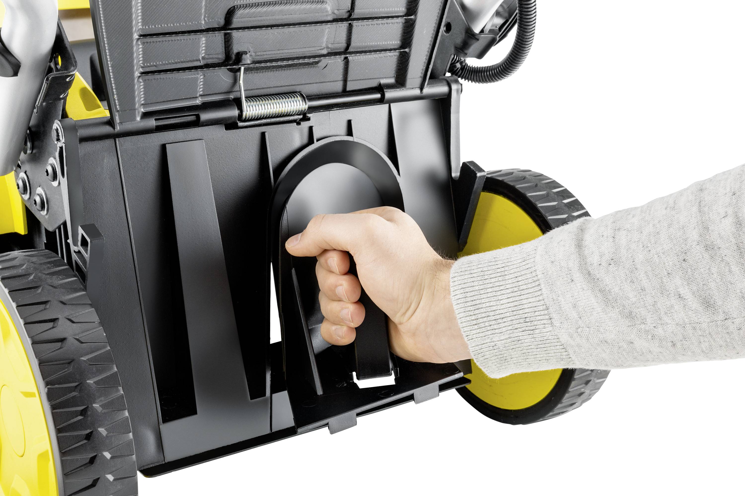 Hand hält den Griff eines Geräts mit schwarzen und gelben Rädern. Funktion oder Zweck des Geräts wird nicht detailliert gezeigt.