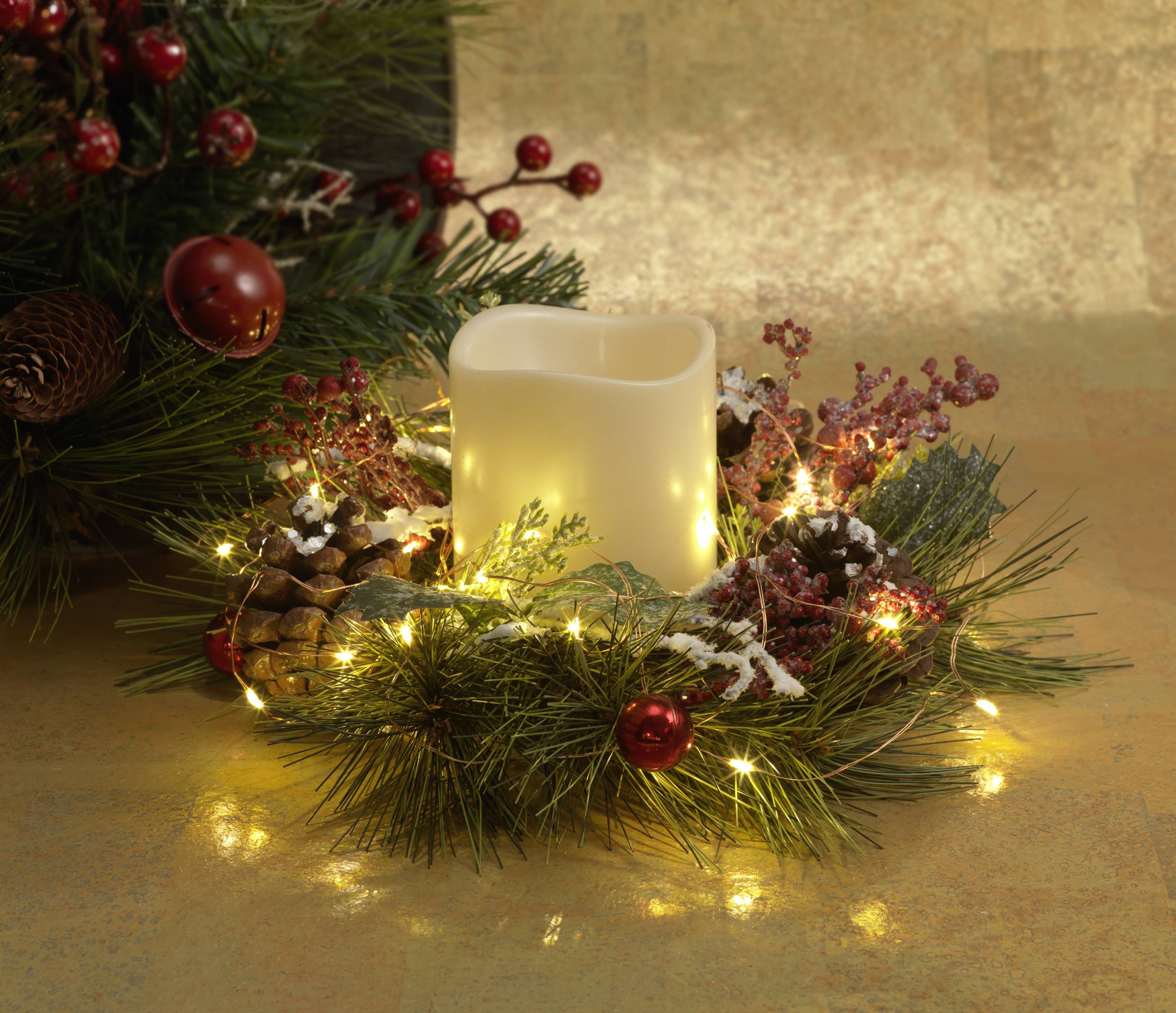 Ein leuchtender Adventskranz mit roten Beeren und Tannenzapfen umgibt eine flammenlose Kerze, winterliche Dekoration.